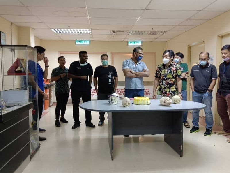 Workshop participants gathered around 3D printed skull models during the hands-on session
